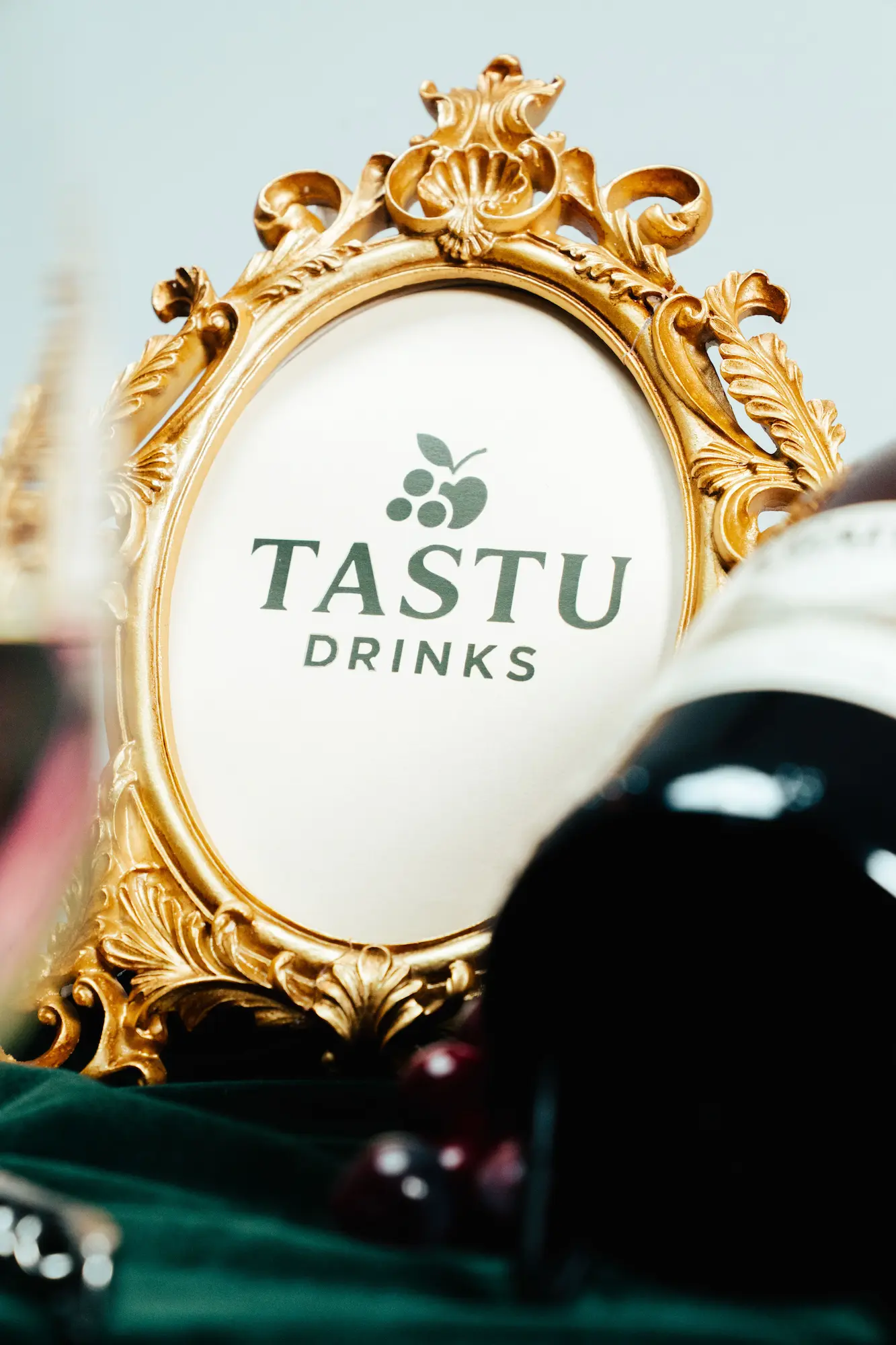 Tastu Drinks - Estaciones de Vino y Sidra Dos copas de vino tinto servidas en primer plano con botellas de sidra y vino premium de Tastu Drink al fondo.