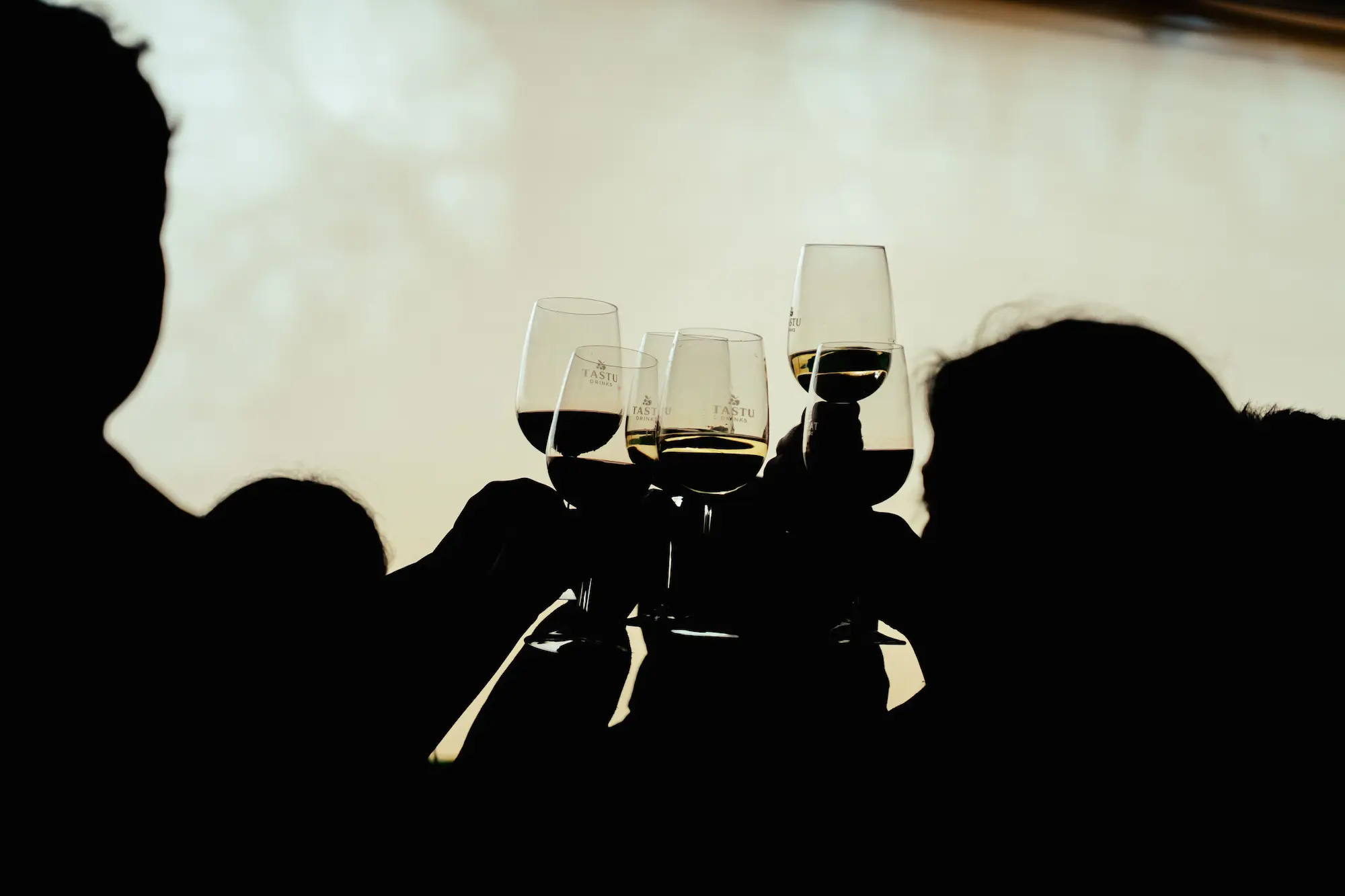 Grupo de personas brindando con copas en alto durante un evento nocturno de Tastu Drink.