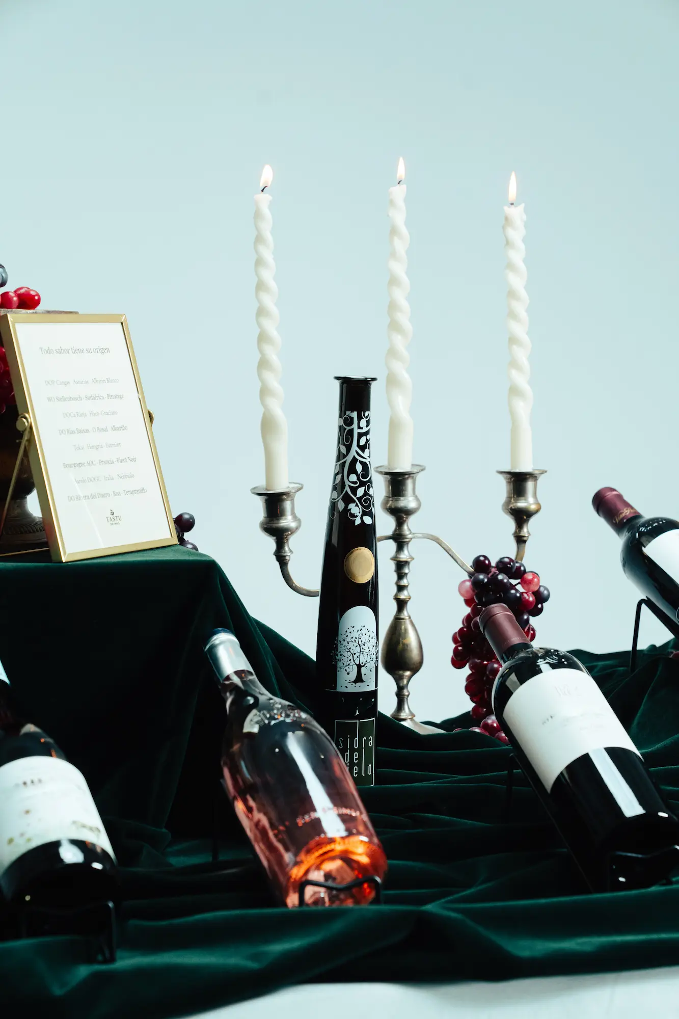 Tastu Drinks - Estaciones de Vino y Sidra Bodegón de Tastu Drink con botella de vino, copa servida y uvas frescas sobre una mesa de madera.